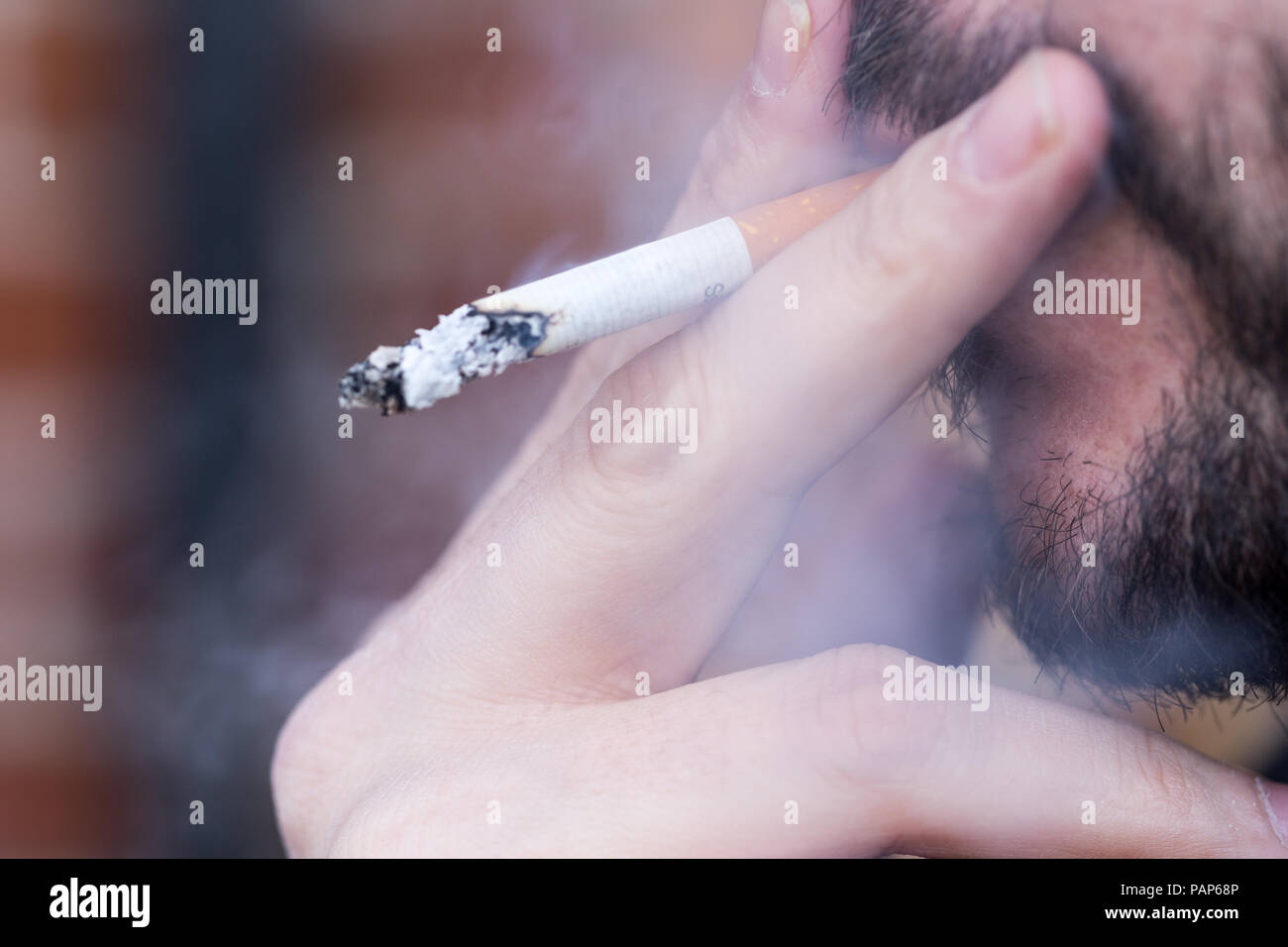 Man raucht eine Zigarette, King Size mit Asche und Rauch Stockfoto