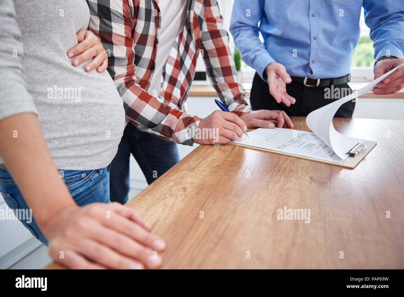Paar mit real estate agent unterzeichnen Vertrag in der Küche der neuen Wohnung Stockfoto