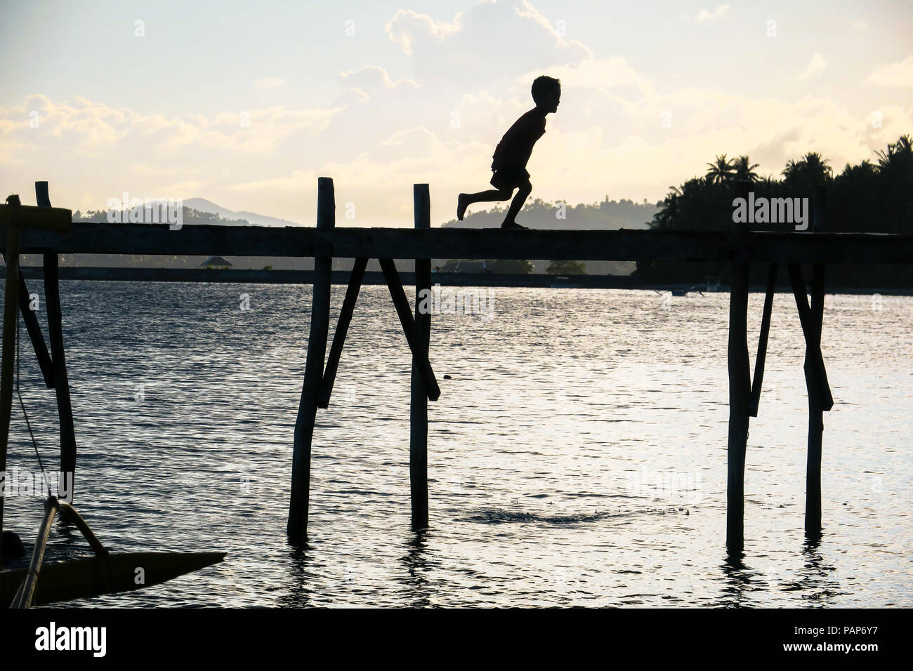Silhouette von Jungen laufen und spielen auf Dorf Insel Dock bei Sonnenuntergang - Allgemeine Luna, Siargao - Philippinen Stockfoto