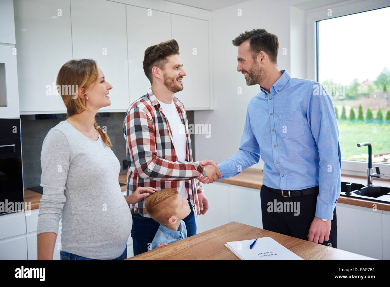 Familie und real estate agent Händeschütteln in der Küche der neuen Wohnung Stockfoto