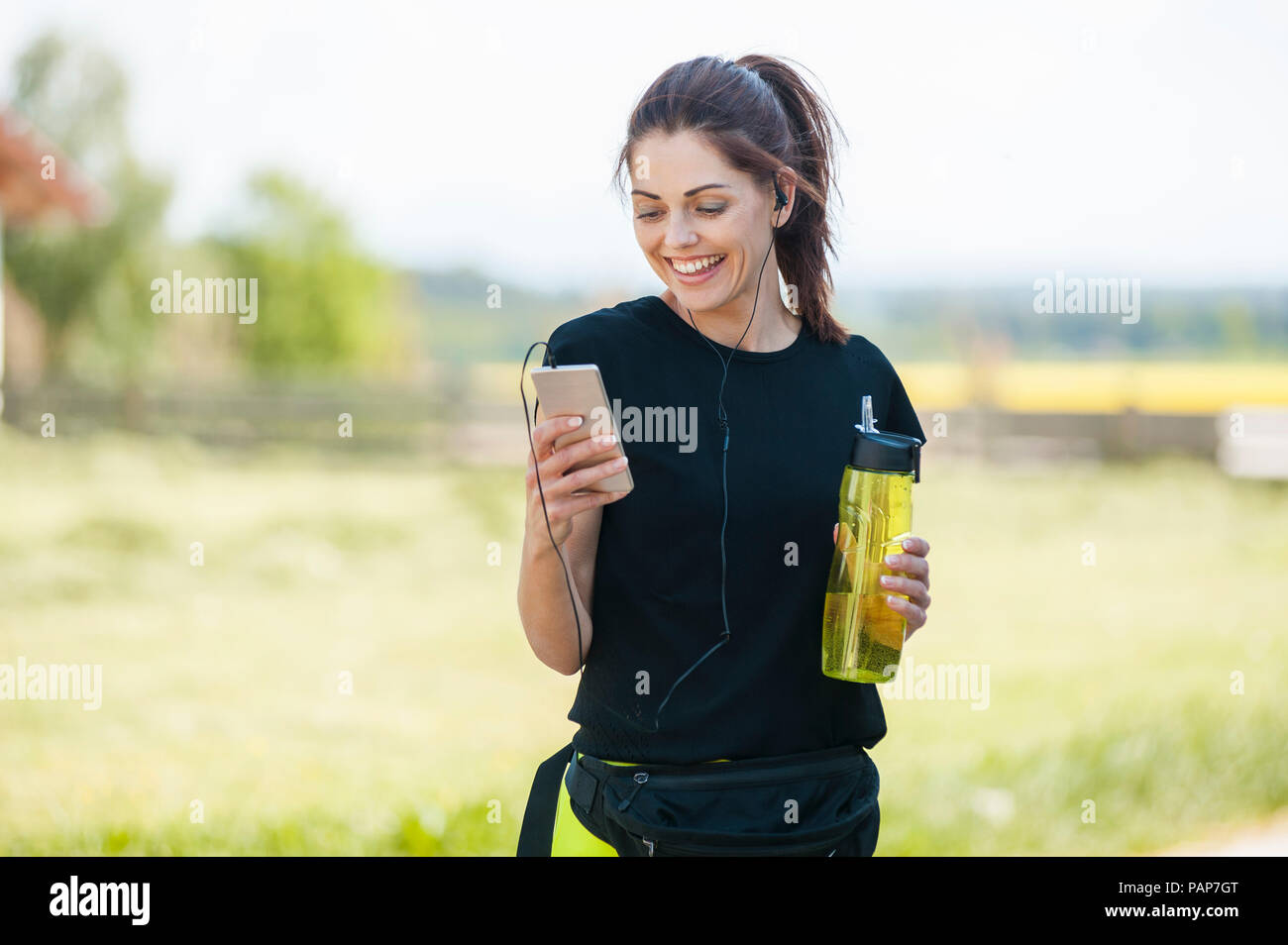 Sportliche Frau mit Smartphone beim Kühlen Pause Stockfoto