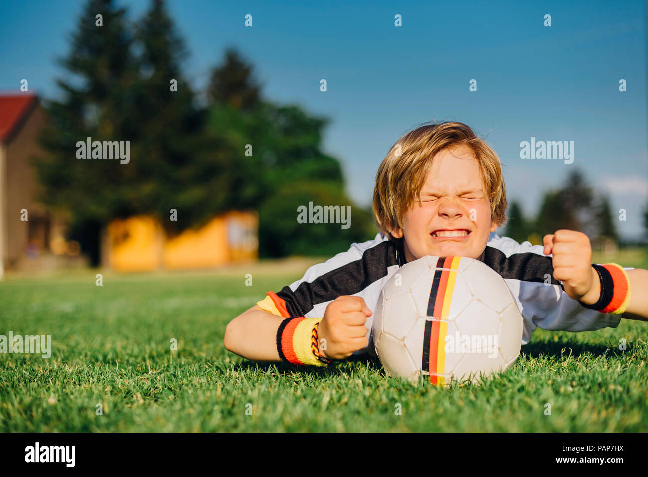 Junge im deutschen Fussball shirt liegen auf Gras und halten die Daumen für Wm gekreuzt Stockfoto