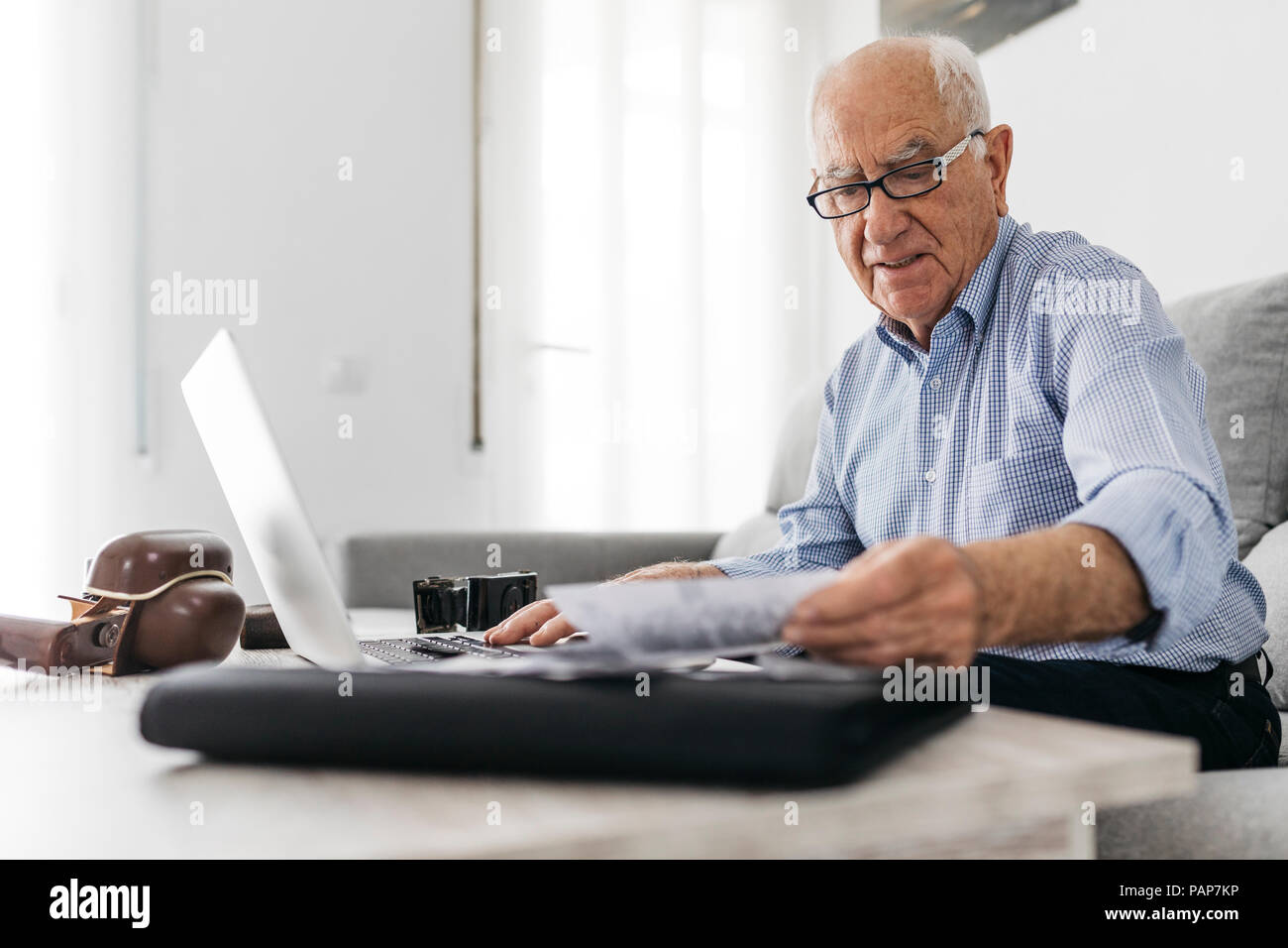 Älterer Mann bei der Arbeit mit einem Computer und seinen alten Fotokameras und alte Fotos Stockfoto