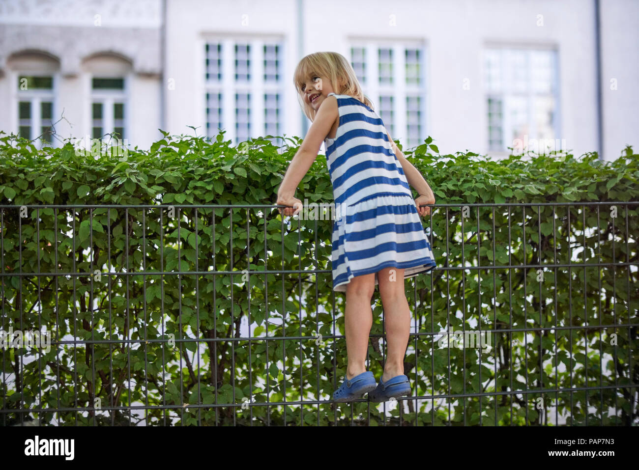 Smuling kleines Mädchen klettern auf Zaun Stockfoto