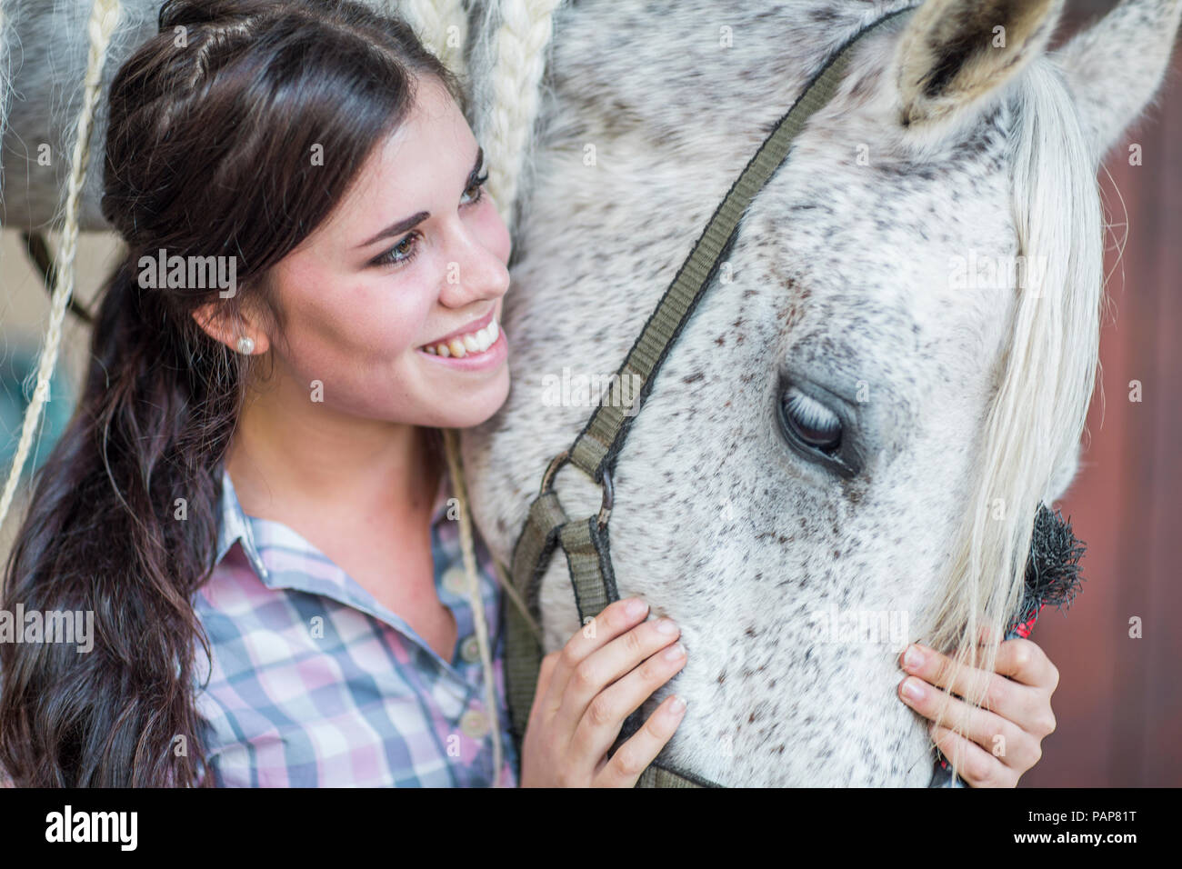 Lächelnde Frau Pflege für ein Pferd auf einem Bauernhof Stockfoto