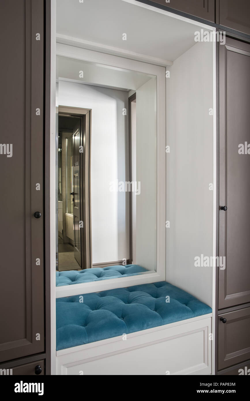 Wunderschönes Hotel Zimmer mit einem braunen Schließfächer und einen weißen  Nische mit einem weichen blauen Sitz und Spiegel. Tür zum Bad ist in dem  Spiegel reflektiert. Schließen Stockfotografie - Alamy