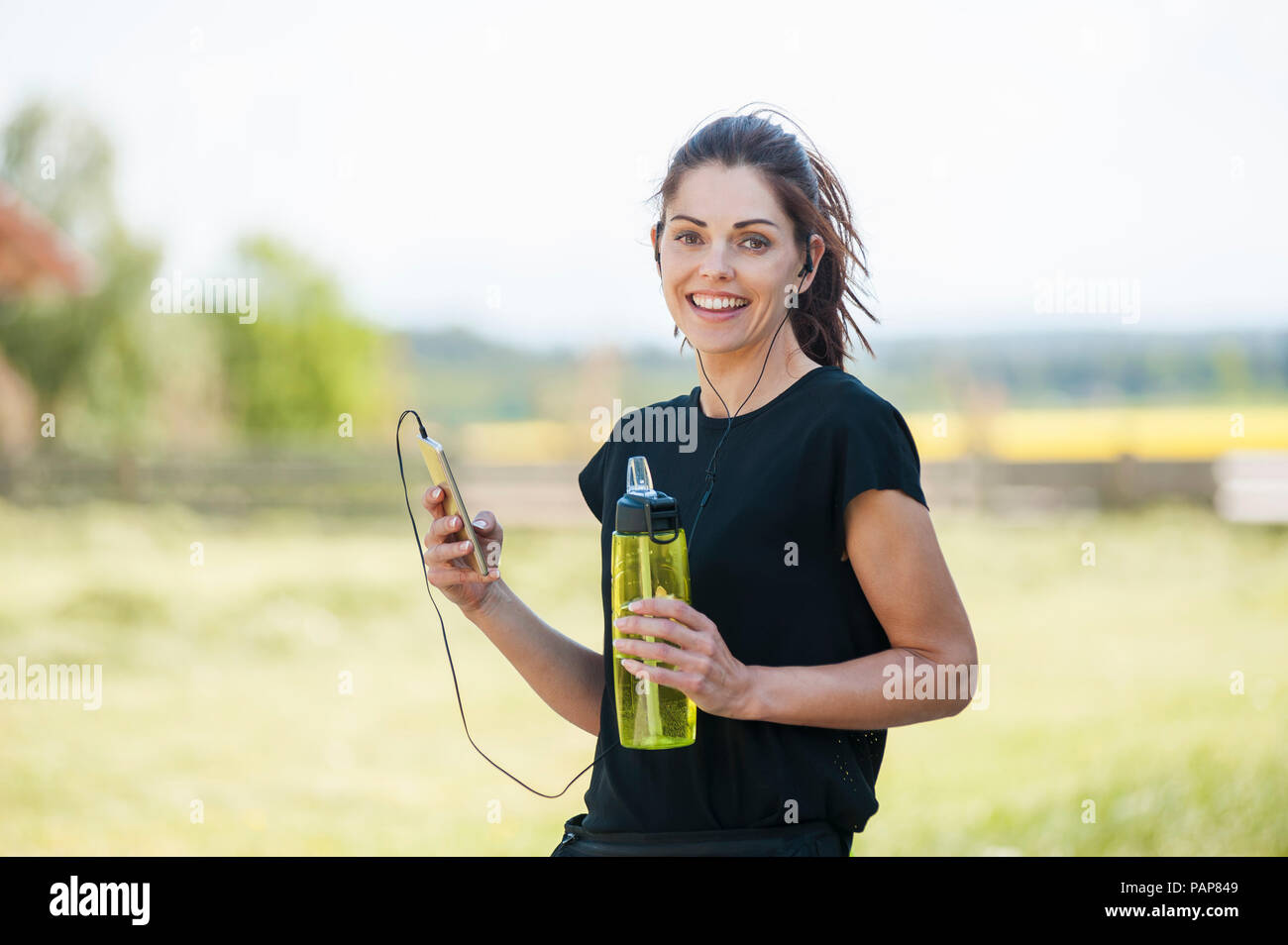 Sportliche Frau mit Smartphone beim Kühlen Pause Stockfoto