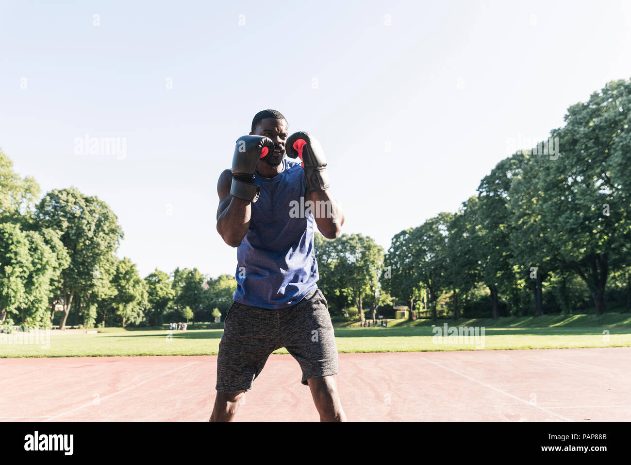 Junge afro-amerikanischer Mann training Boxen auf Sportplatz, im Freien Stockfoto
