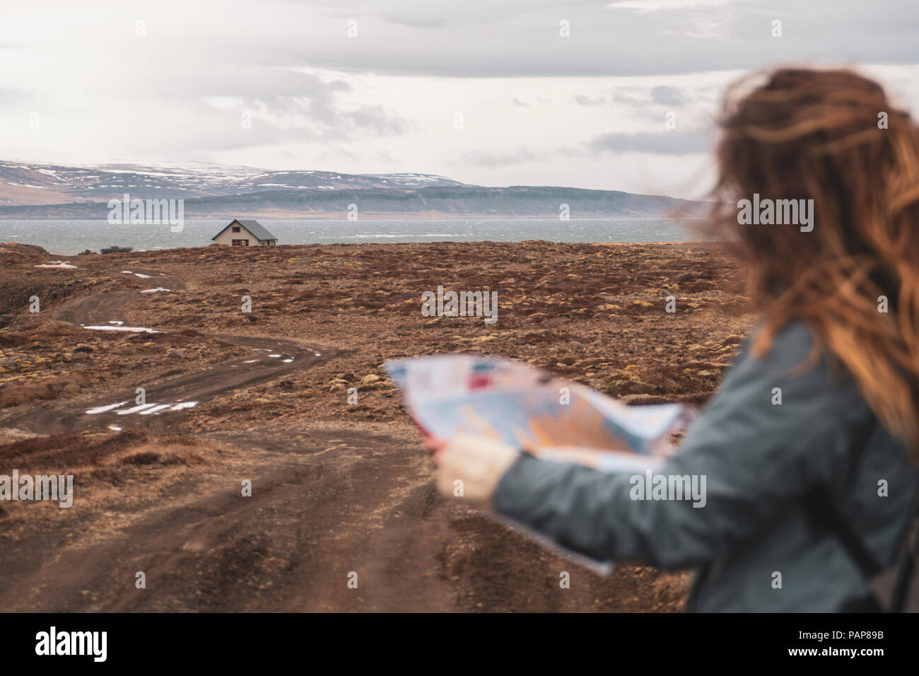 Island, Frau mit Karte in der Landschaft mit Haus Stockfoto