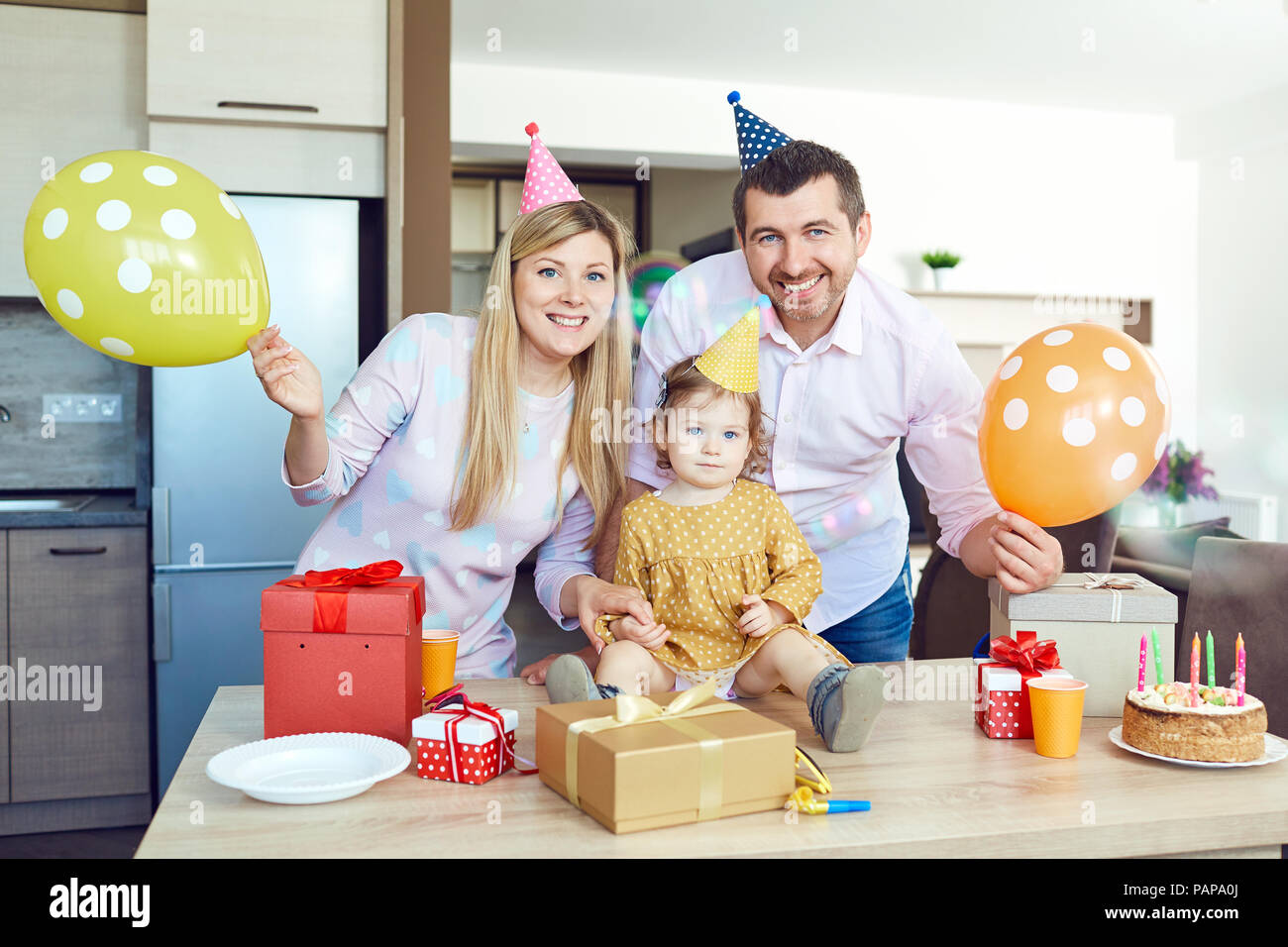 Eine Familie mit einem Kuchen gratuliert ein glückliches Kind an seinem Geburtstag Stockfoto