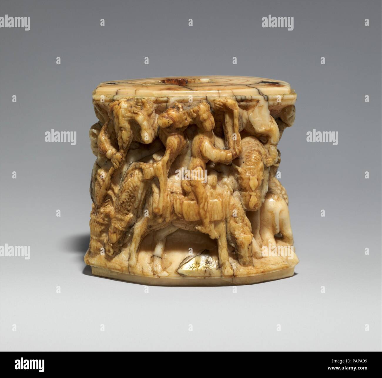 Dekorative montieren. Kultur: Deutsch. Abmessungen: 2 3/8 x 2 5/8 x 1 3/4 in. (6 × 6,6 × 4,5 cm). Datum: Ca. 1375-1400. Dieses rätselhafte Objekt ist in der hohen Relief geschnitzt. Weder die ursprüngliche Funktion noch die Erzählung sind bekannt, aber der Stil der Schnitzerei deutet darauf hin, dass es in Deutschland im späten 14. Jahrhundert gemacht wurde. Auf der einen Seite vier Löwen sind vor dem Hintergrund der Bäume dargestellt. Die andere Seite zeigt vier männlichen Equestrian zahlen. Auf der linken Seite der gekrönte Figur eines alten, bärtigen Mann lehnt sich nach vorn, da sein Pferd senkt seinen Kopf zu essen oder zu trinken. Der Mensch bringt seine linke Hand zu seinem Auge, perhap Stockfoto