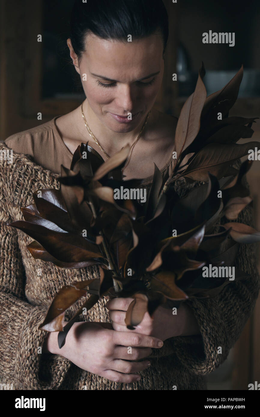 Frau mit Bündel Reisig mit braunen Blätter Stockfoto