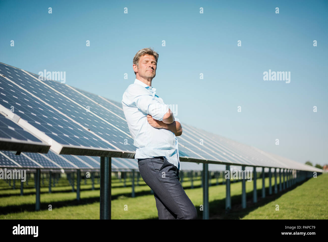 Reifer Mann mit geschlossenen Augen lehnte sich auf Solar Panel Stockfoto