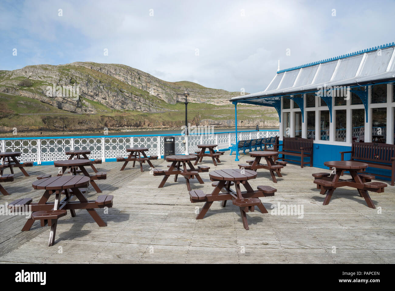 Picknick-bänken auf Llandudno Pier mit dem Great Orme im Hintergrund, North Wales, UK. Stockfoto