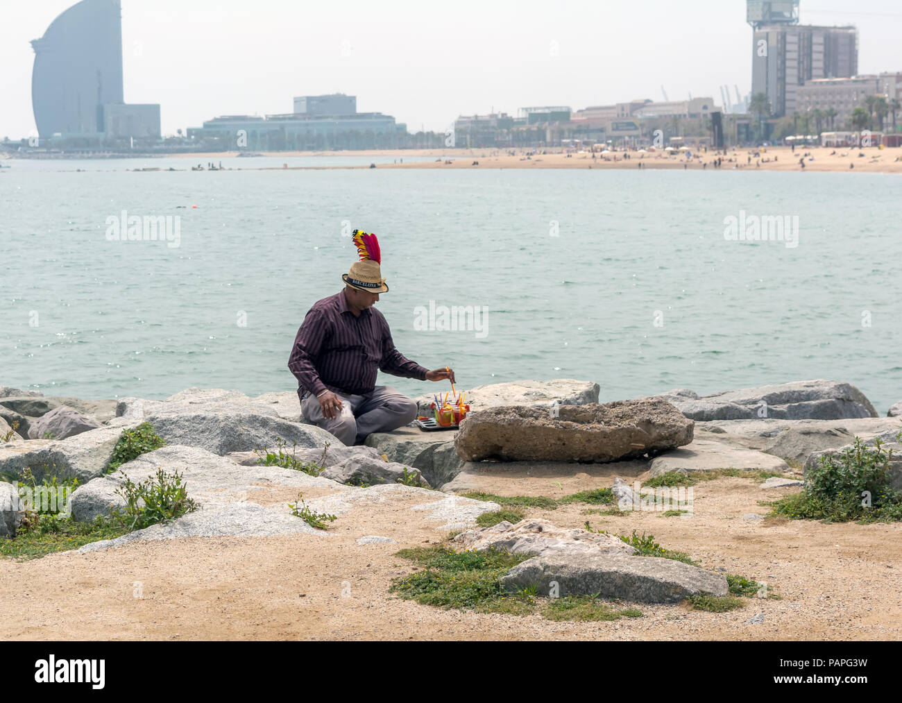 Getränke' Verkäufer sitzend mit Seiner vendibles auf der Mole an der Barceloneta Strand am Mittelmeer. Stockfoto