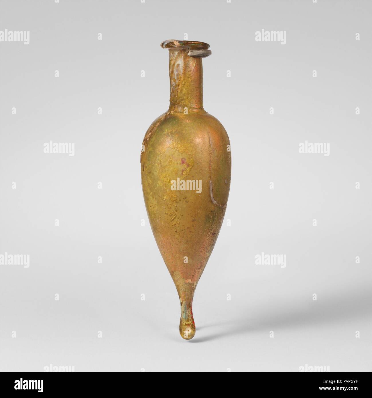 Glas Parfüm Flasche. Kultur: Roman. Abmessungen: 4 1/2 in. (11,5 cm) Andere: 1 3/8 in. (3,5 cm) Durchm. Von rim: 3/4 in. (2 cm). Datum: 1. Jh. N.CHR.. Transparente grünlich-gelb. Ungleichmäßige rim ausgeklappt, rund, und in; zylindrische Hals, leicht nachgerüstet, um Base; längliche piriform Körper, verjüngt sich solide, Knopf mit Tooling Gedankenstrich in einer Seite. Intakt; pinprick blasen; Mattierung, tiefe Rillen und Verwitterung, ein brillanter irisierenden Oberfläche auf der Außenseite. Farblose ovale Vase aus mundgeblasenem Glas mit spitzer Basis und schlanken Hals. Museum: Metropolitan Museum of Art, New York, Stockfoto