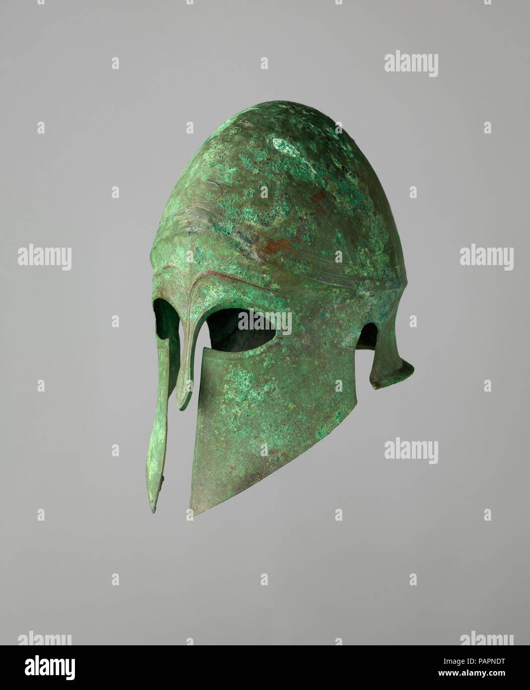Helm der Korinther Art und ein paar Grieben. Kultur: Griechisch. Abmessungen: Helm: H. 12 1/16-in. (30,6 cm); W. 7 1/4 in. (18,5 cm); D.10 13/16-in. (27,4 cm); Wt. 2 lb. 0,85 oz. (931 g); Recht Beinschiene: H.15 cm. (39,1 cm); W. 4 15/16 in. (12,5 cm); D.6 3/8 in. (16,2 cm); Wt. 1 lb. 2.5 oz. (525 g); links Beinschiene: H.15 7/16 in. (39,2 cm); W. 5 1/4 in. (13,3 cm); D.6 1/16-in. (15,4 cm); Wt. 1 lb. 1.4 oz. (492 g). Termin: Anfang 5. Jahrhundert v. Chr.. Dieser Helm und ein paar Grieben (Shin Guard), oder <i> cnemids</i>, ergänzend zu den wichtigsten Elementen einer ganzen Palette gehören, die offensiv Stockfoto