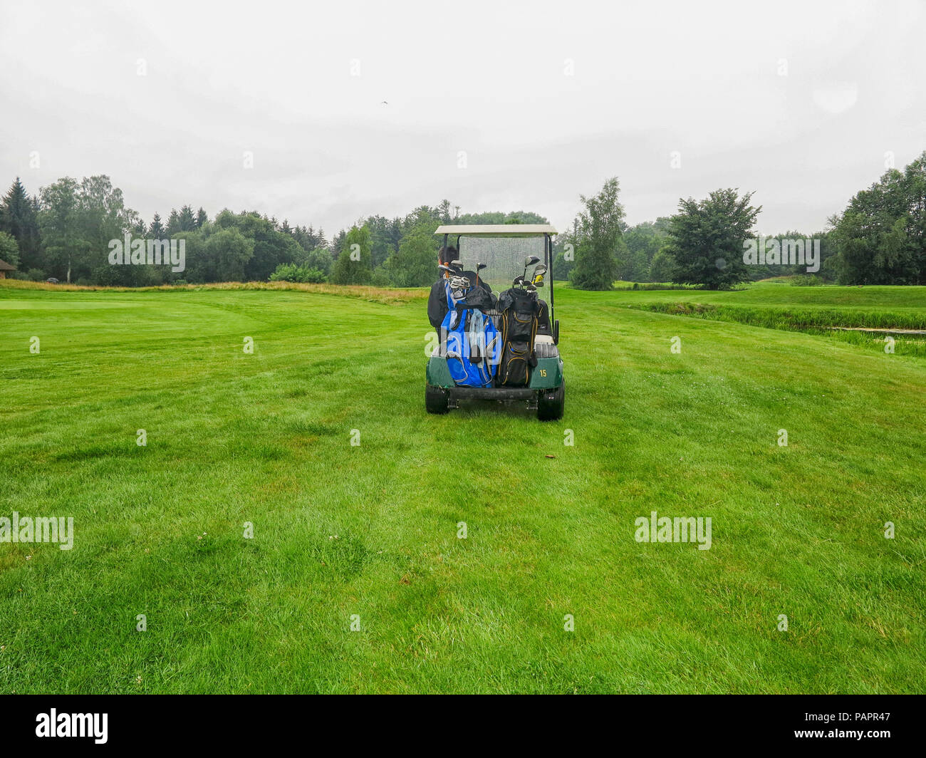 Mann in golfcart auf Fahrrinne in Regen Stockfoto