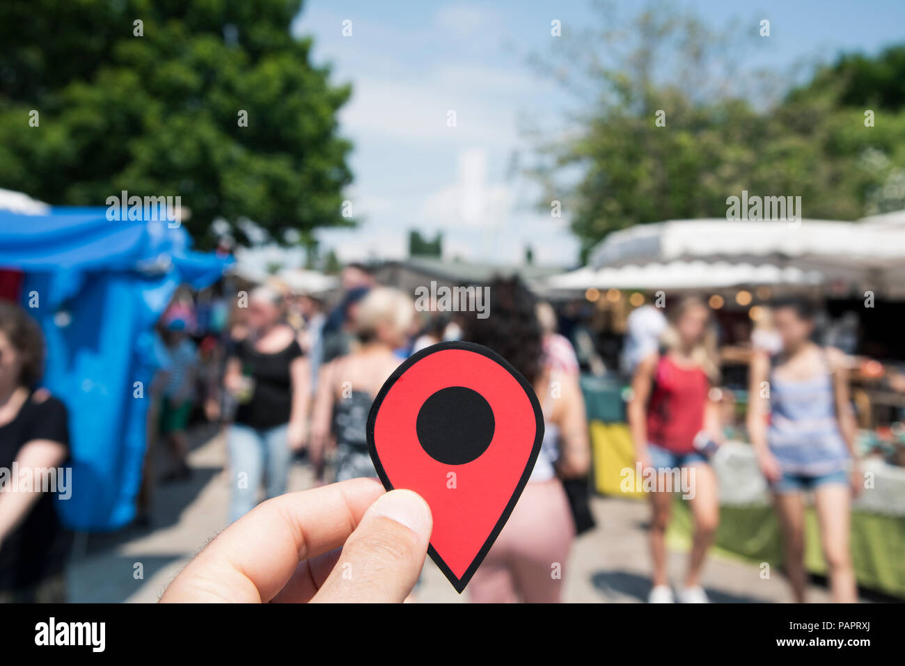 Die Hand eines jungen Mannes mit Eine rote Markierung auf einer Straße Marker mit unkenntlich Leute im Hintergrund Stockfoto