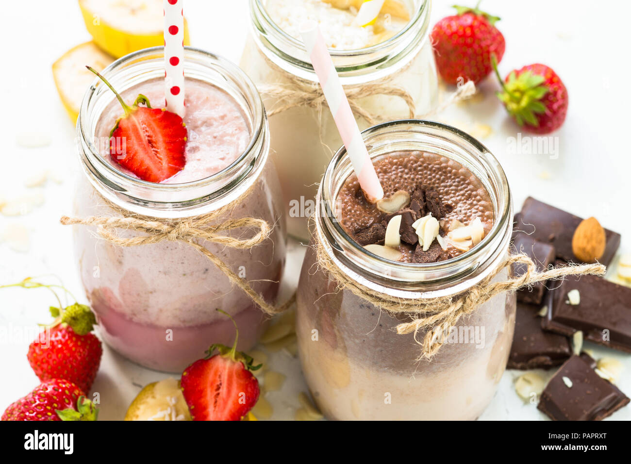 Satz von milchshake in Töpfen. Banane Schoko und Erdbeere Milchshakes mit Muttern und Kokosnuss. Sommer Nachtisch. Gesundes Essen. Stockfoto
