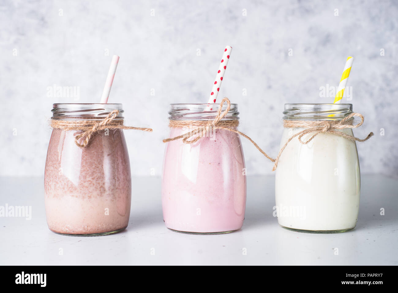 Satz von milchshake in Töpfen. Banane Schoko und Erdbeere Milchshakes mit Muttern und Kokosnuss. Sommer Nachtisch. Gesundes Essen. Stockfoto
