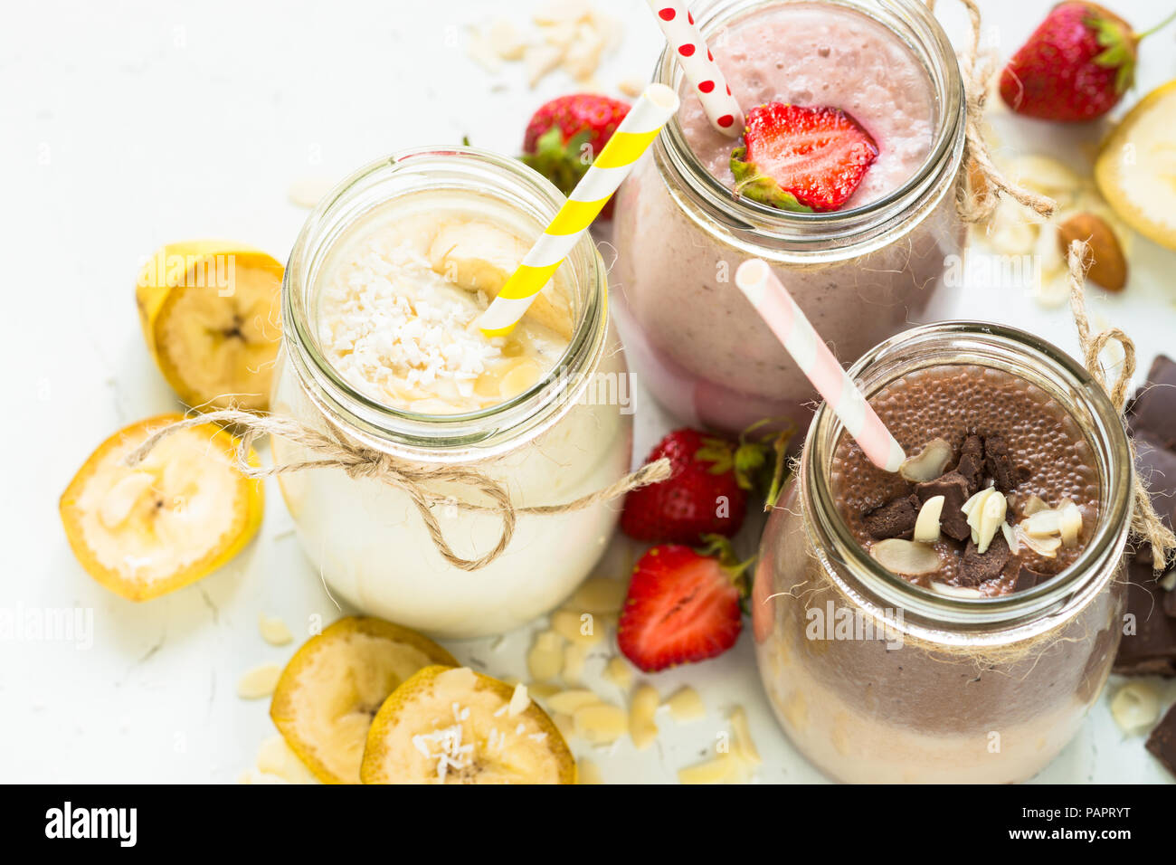 Satz von milchshake in Töpfen. Banane Schoko und Erdbeere Milchshakes mit Muttern und Kokosnuss. Sommer Nachtisch. Gesundes Essen. Stockfoto