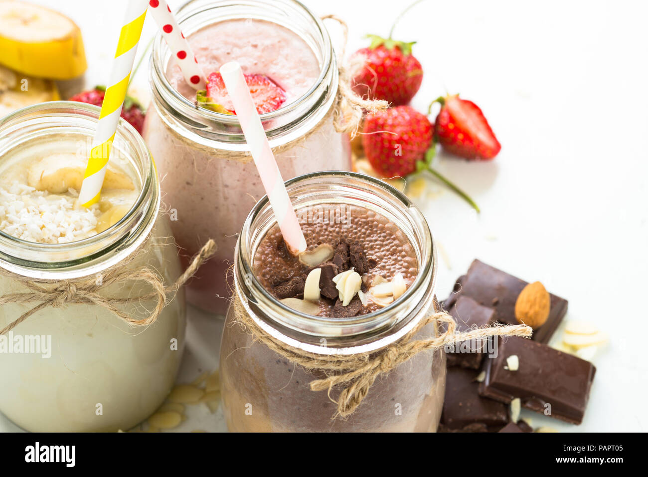 Satz von milchshake in Töpfen. Banane Schoko und Erdbeere Milchshakes mit Muttern und Kokosnuss. Nahaufnahme Stockfoto