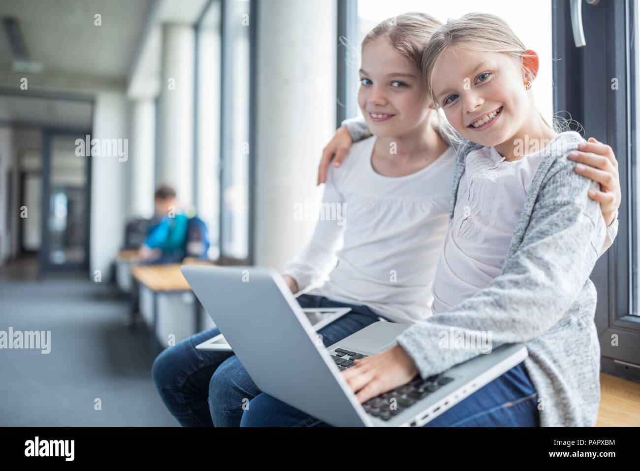 Portrait von zwei lächelnde Schülerinnen mit Notebook und Tablet-PC umarmt Stockfoto