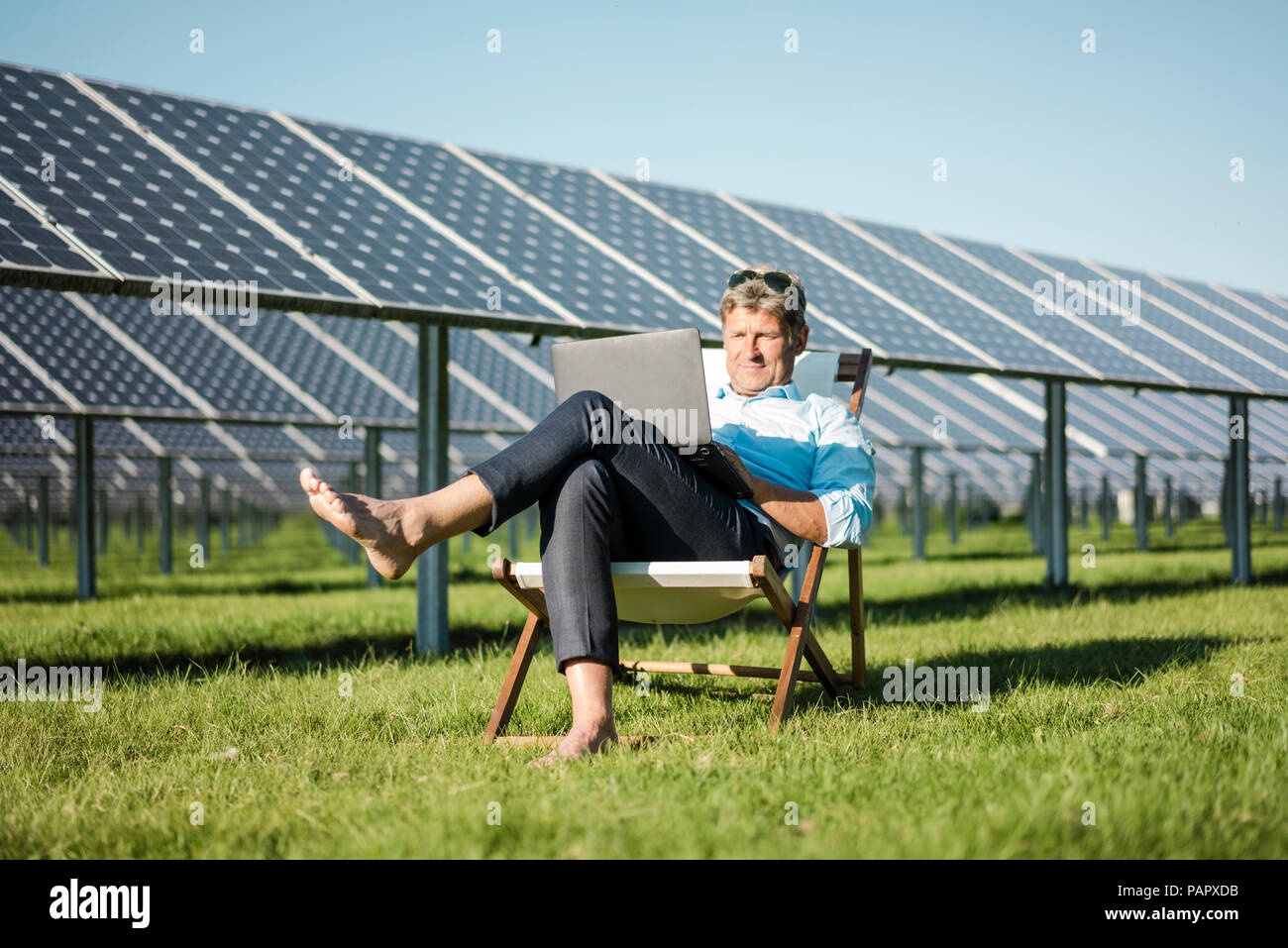 Reifer Mann sitzen am Strand Liege, mit Laptop, Solaranlage Stockfoto