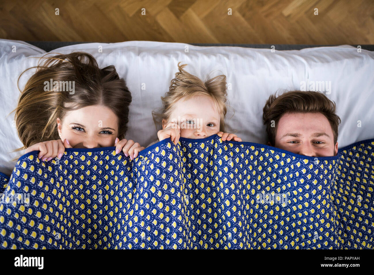 Happy Family im Bett liegt, versteckt unter Vertrag Stockfoto