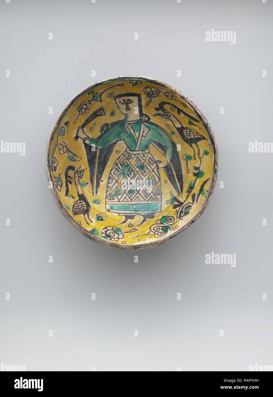 Zwei Schalen mit Zahlen und ein Footed Platte mit Vögeln. Abmessungen: H.3 5/8 in. (9,2 cm) Durchm. 7 7/8 in. (20 cm). Datum: 10. Häufig unter den Buff ware Schalen, die bildlich darstellen, menschliche Figuren sind diejenigen, die trinken Schiffe. In diesem Fall, ein Mann, der eine grüne Tunika unter einem bunten Rock - wie Kleidungsstück besitzt einen geriffelten Becher in der rechten Hand. Die Bilder, die auf diese Schalen aus Metall der Sassanidischen Periode (3. bis 7. Jahrhundert) im Iran abzuleiten. Die charakteristischen gelben und grünen Glasuren der Buff ware Gruppe sind besonders gut auf diesem Beispiel erhalten. Museum: Metropoli Stockfoto