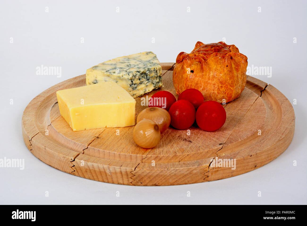 Plowmans Mittagessen auf einem Holzbrett bestehend aus Pork Pie, Stilton Cheese, Cheddar Käse, Tomaten und eingelegte Zwiebeln, England, UK, Europa. Stockfoto