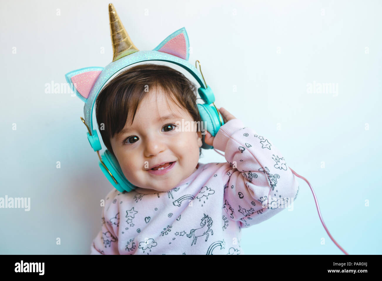 Portrait von lächelnden Mädchen mit Unicorn Kopfhörer Musik hören Stockfoto