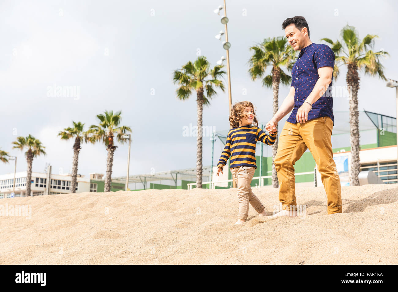 Spanien, Barcelona, Vater und Sohn gehen Hand in Hand am Strand Stockfoto