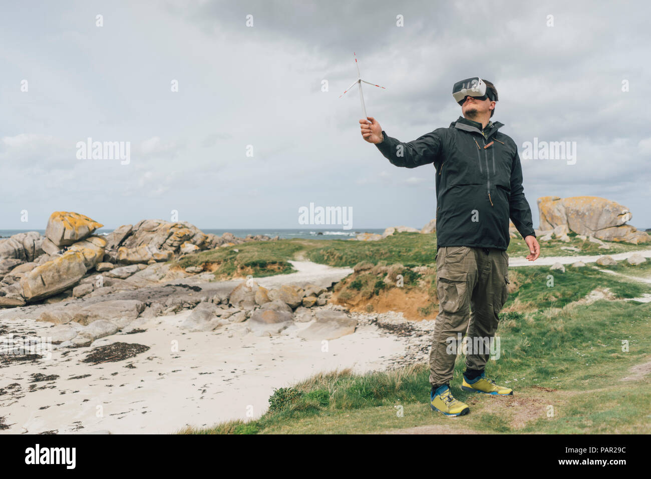 Frankreich, Bretagne, Meneham, Mann mit Miniatur wind turbine tragen VR-Brille an der Küste Stockfoto