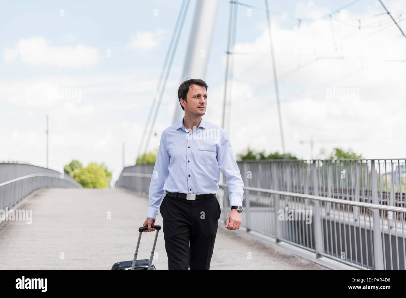 Geschäftsmann mit rollenden Koffer über eine Brücke Stockfoto