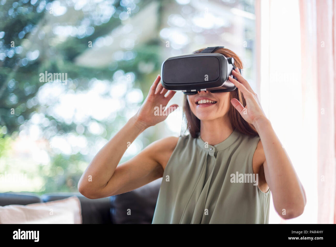 Lächelnde Frau zu Hause VR-Brille tragen Stockfoto