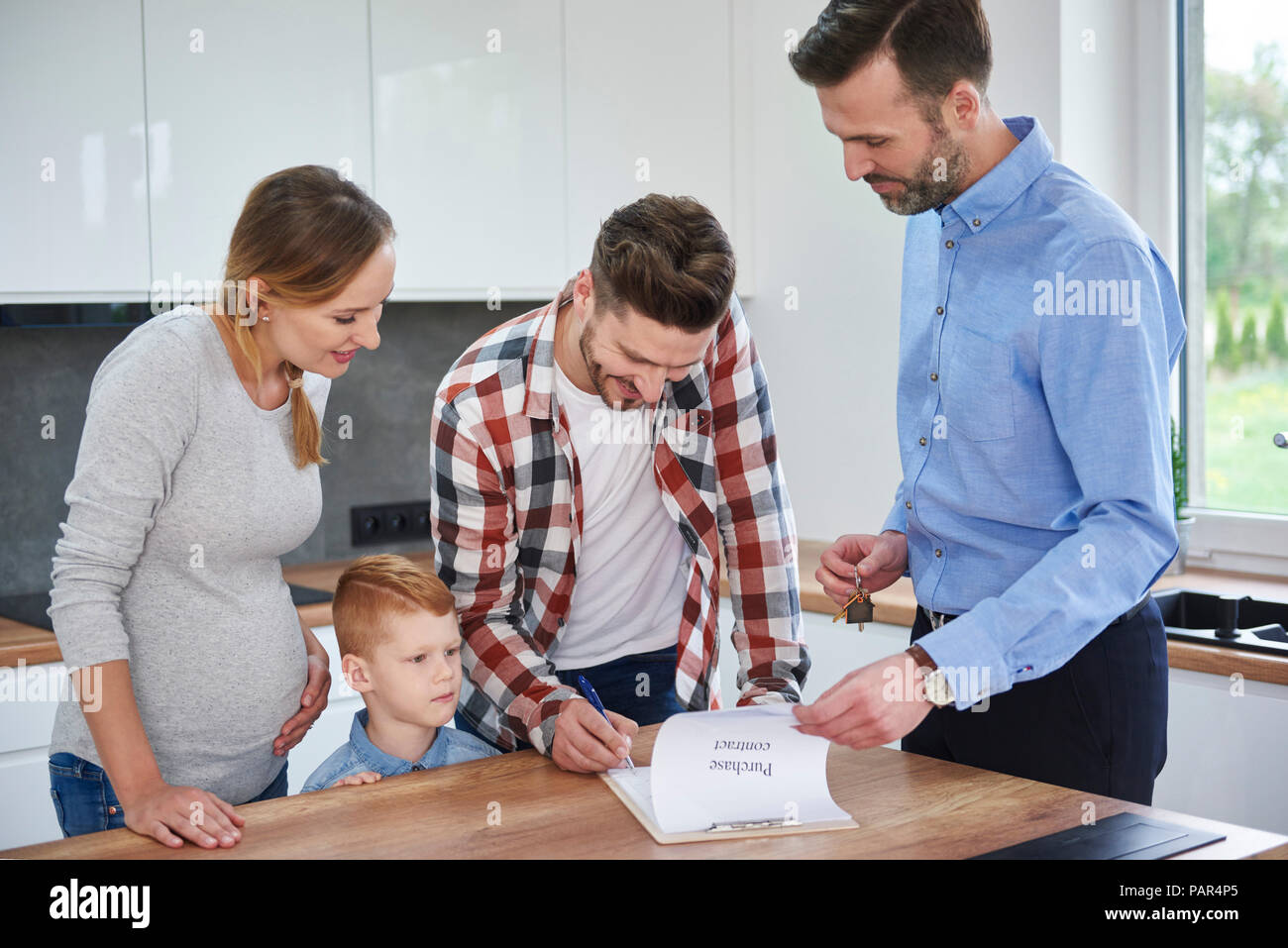 Familie mit real estate agent unterzeichnen Vertrag in der Küche der neuen Wohnung Stockfoto