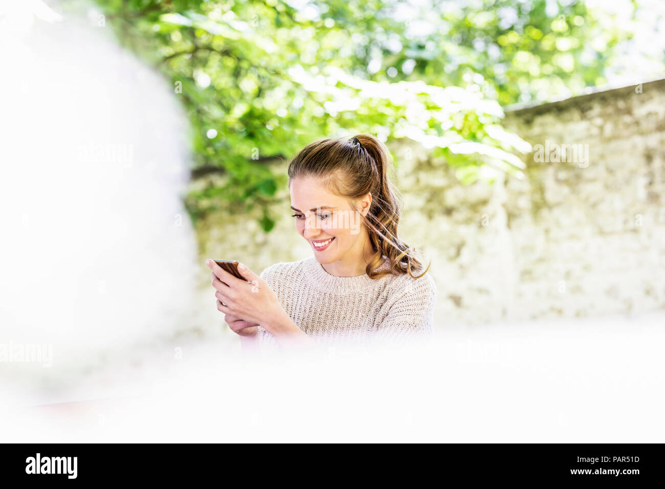 Lächelnde Frau Blick auf Handy-im freien Stockfoto