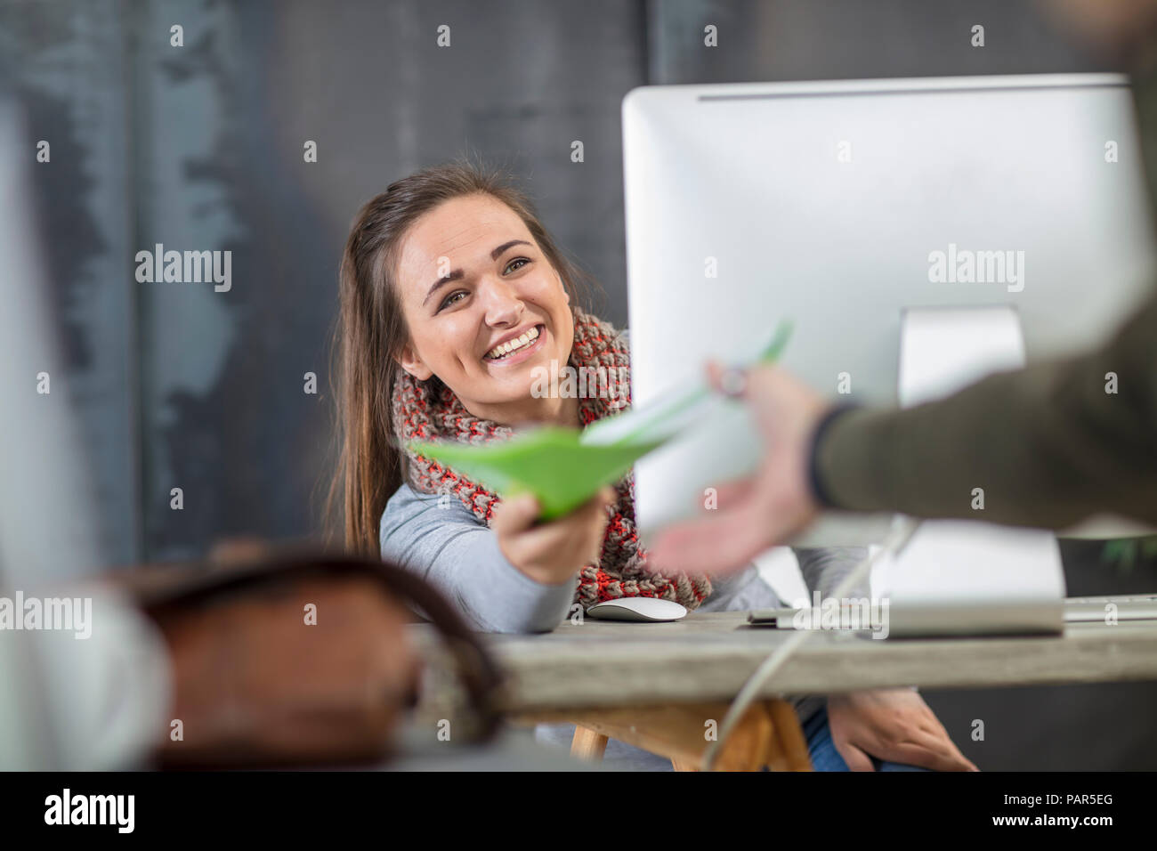 Glückliche junge Frau, die Übergabe von Dokumenten in Office Stockfoto