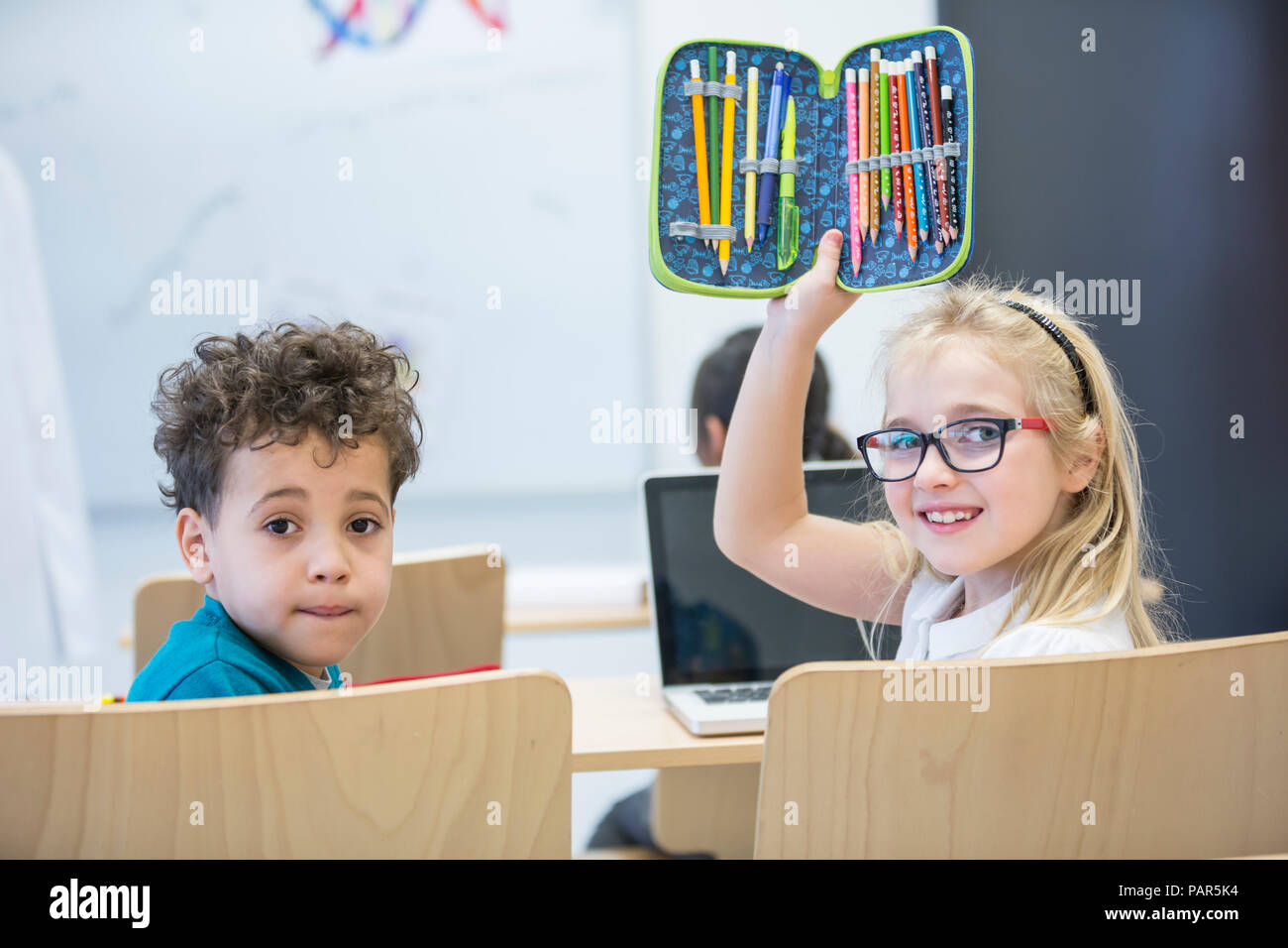 Portrait von Schüler und Schülerin mit Laptop und Federmäppchen in der Klasse Stockfoto