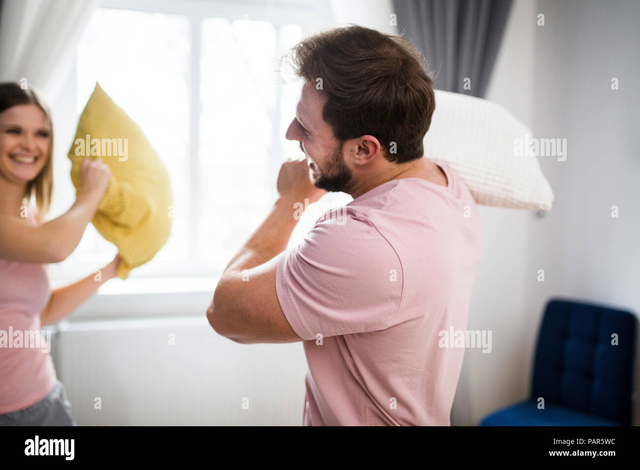 Glückliches Paar, das Spaß im Schlafzimmer, mit einer Kissenschlacht Stockfoto