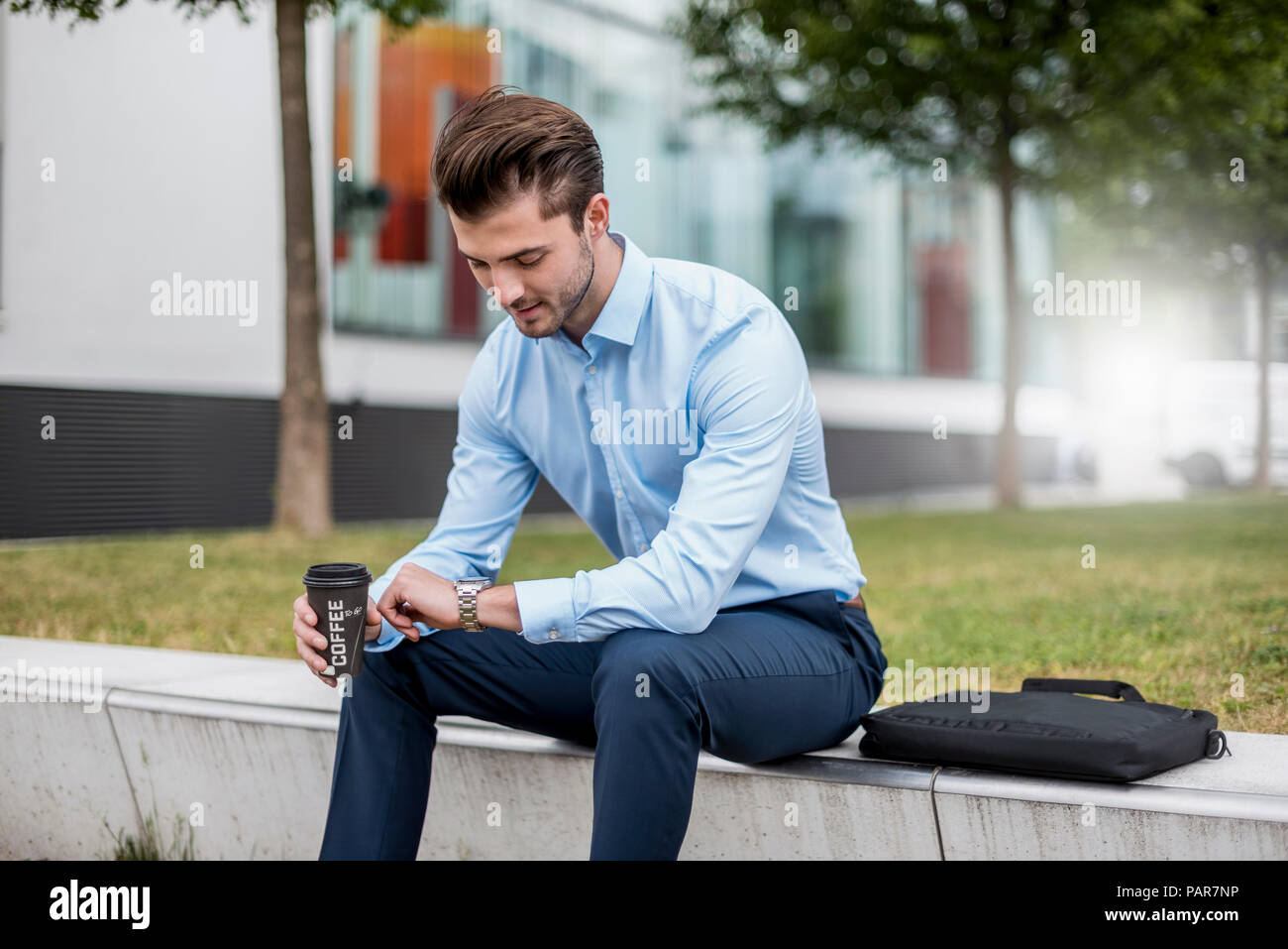 Junge Unternehmer Sitzen im Freien mit Kaffee zum Mitnehmen das mal prüfen. Stockfoto