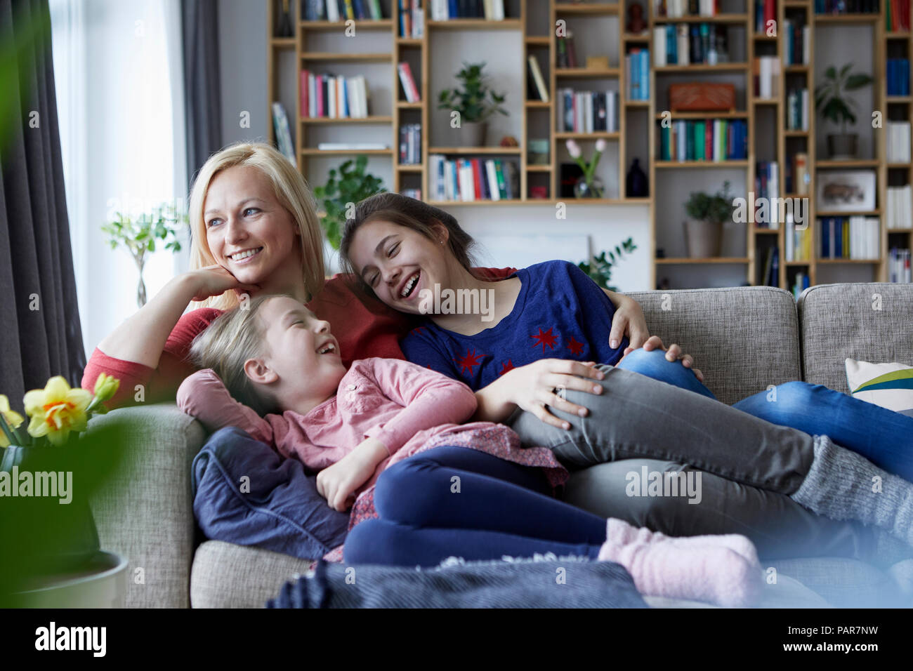 Mutter und ihre Töchter kuscheln und Spaß haben, sitzen auf der Couch Stockfoto