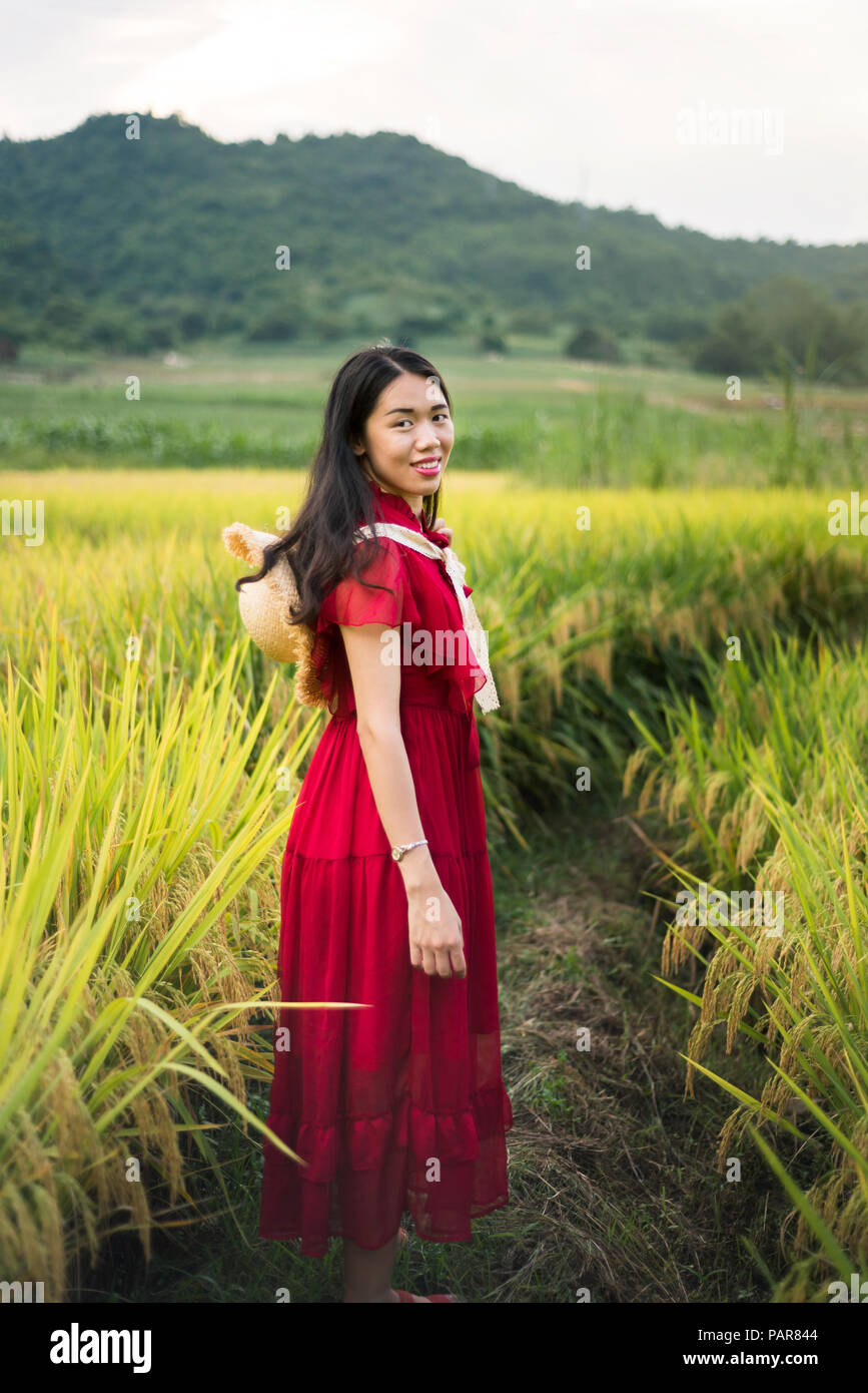 Mädchen in einem Reisfeld das Tragen der roten Kleid und einem Hut Stockfoto