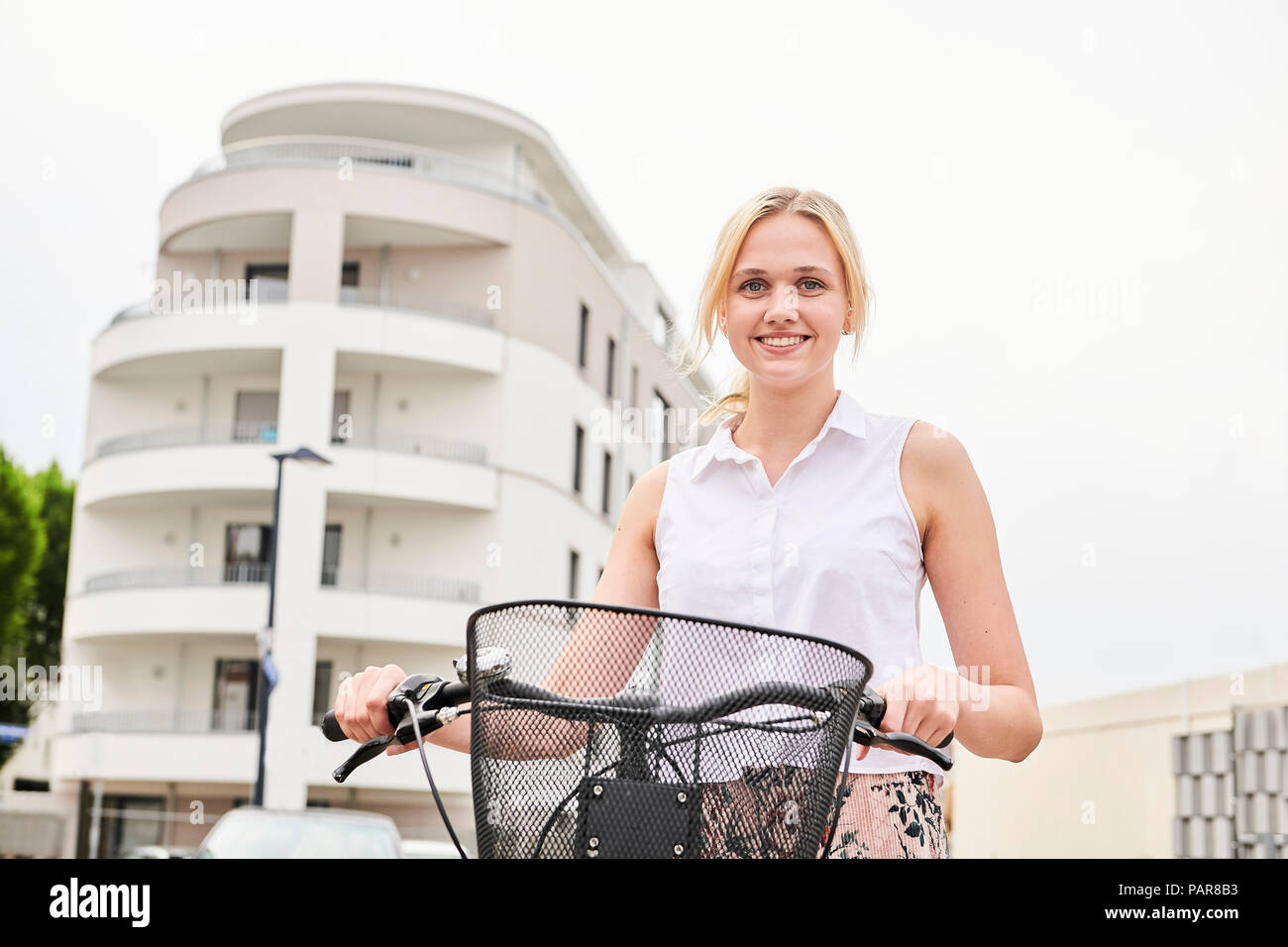 Portrait von lächelnden jungen Frau mit Fahrrad Stockfoto
