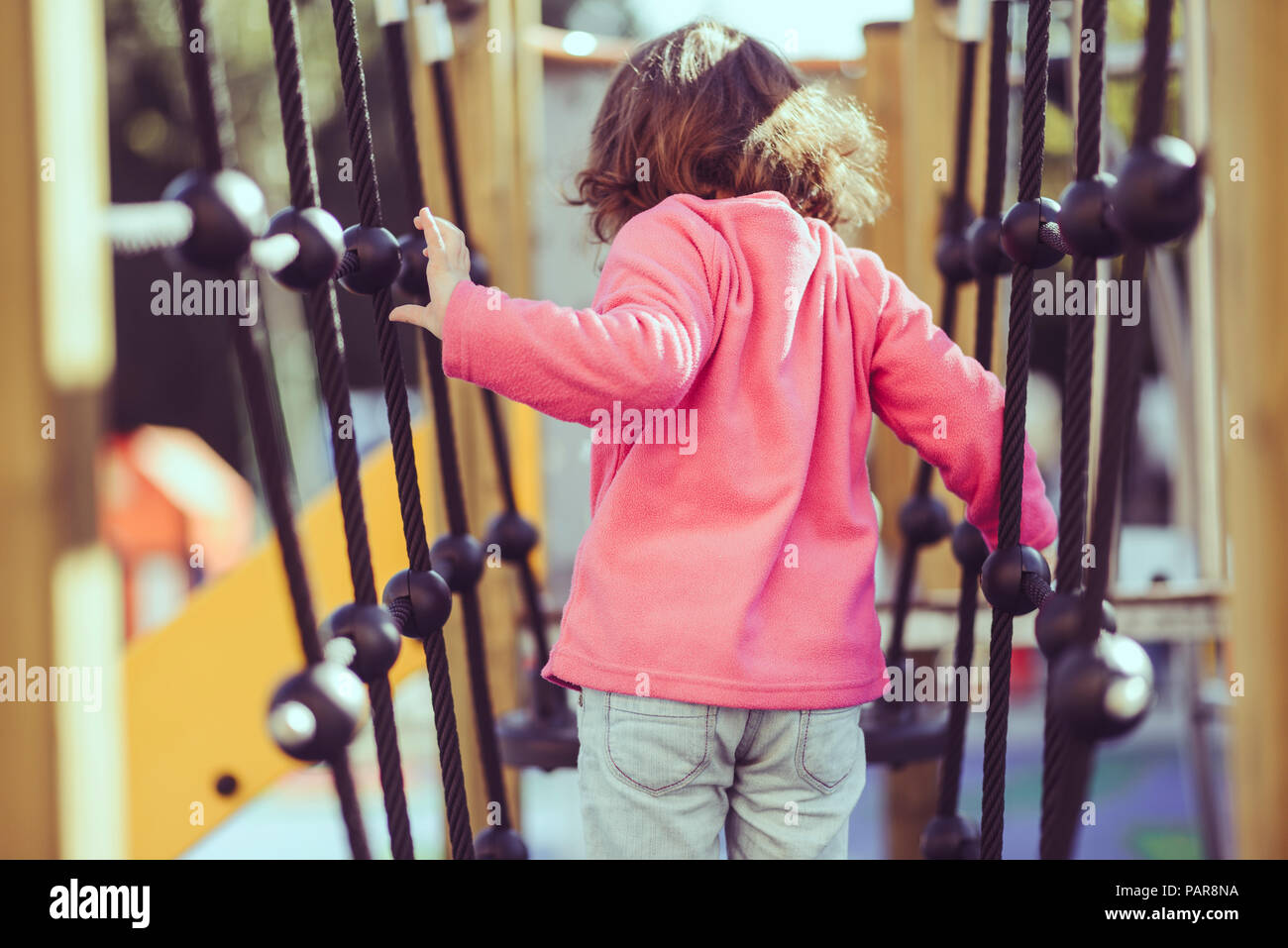 Rückansicht des kleinen Mädchens auf klettergerüst am Spielplatz Stockfoto