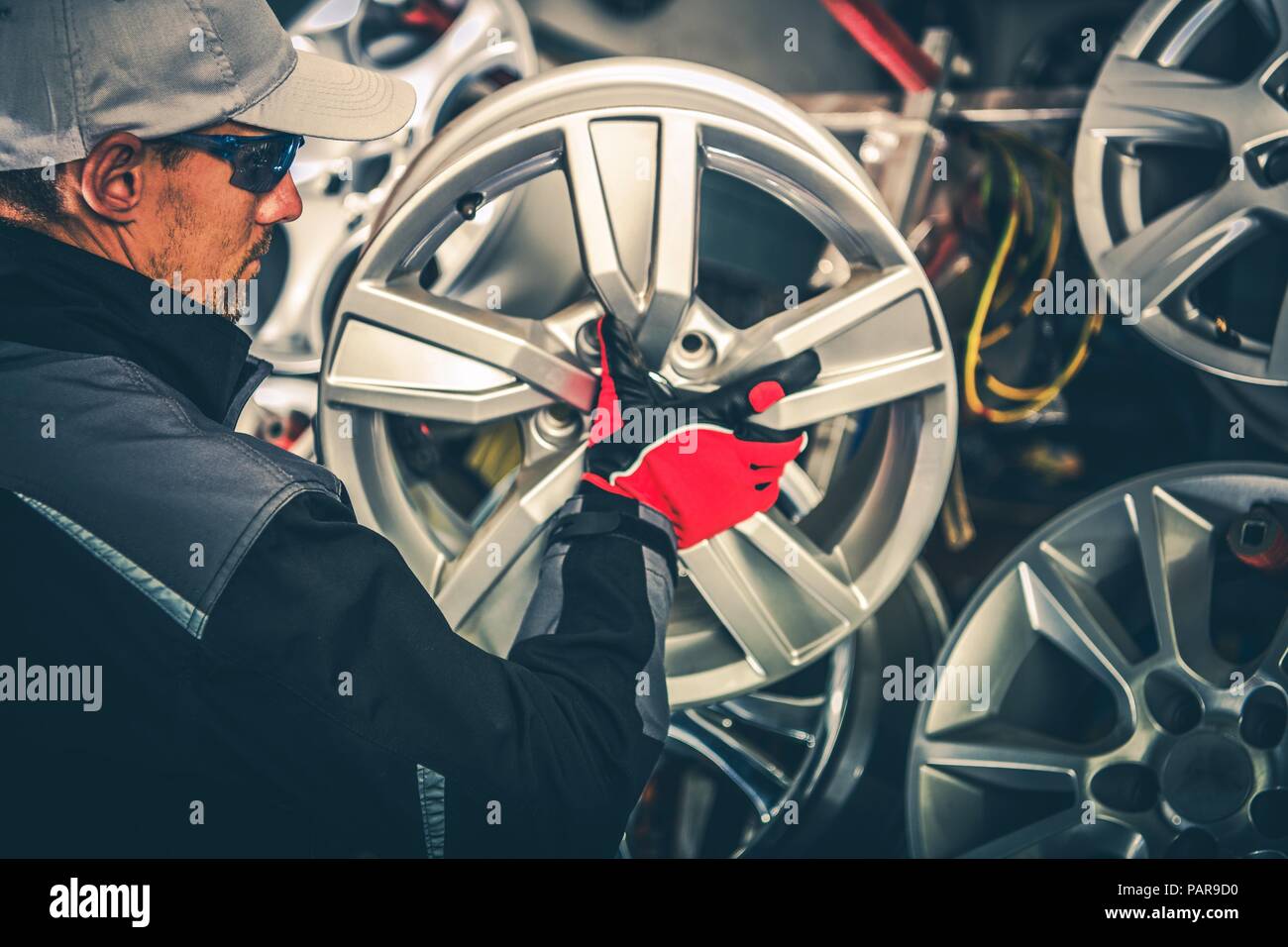Kauf neue Leichtmetallräder und saisonale Reifen wechseln Konzept Foto. Kaukasische Car Service Arbeiter mit großen Rim in den Händen. Stockfoto
