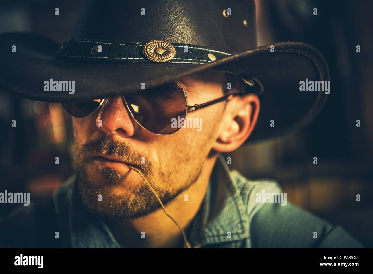 Kaukasische Cowboy in seinem 30s mit Gras Stroh in den Mund.. Foto im Hochformat. Stockfoto