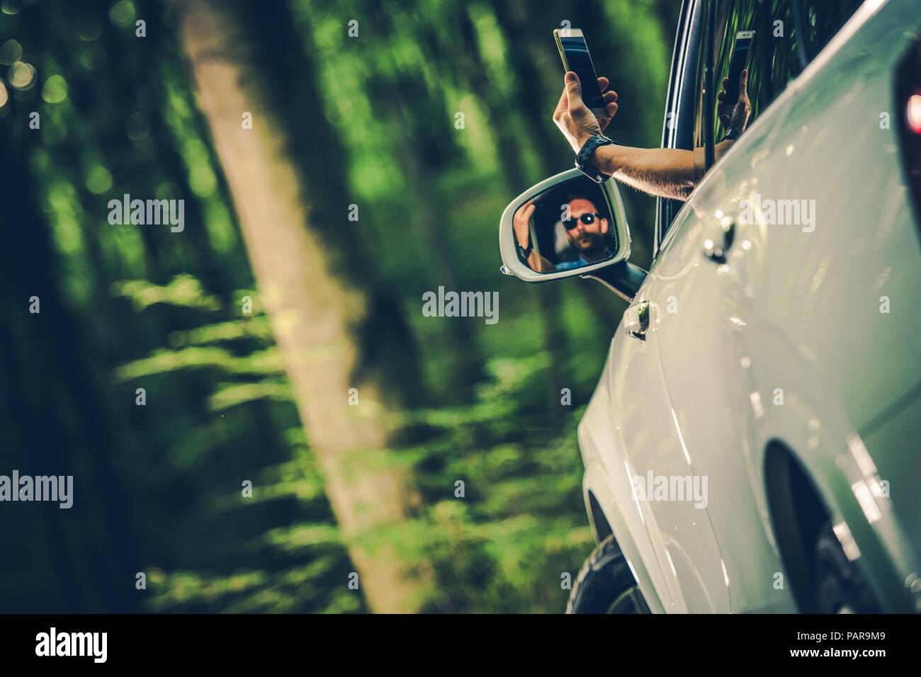 Verloren Callular Rezeption. Kaukasische Männer versuchen, zu finden Telefon Signal sein Smartphone aus dem Auto heraus zu halten. Stockfoto